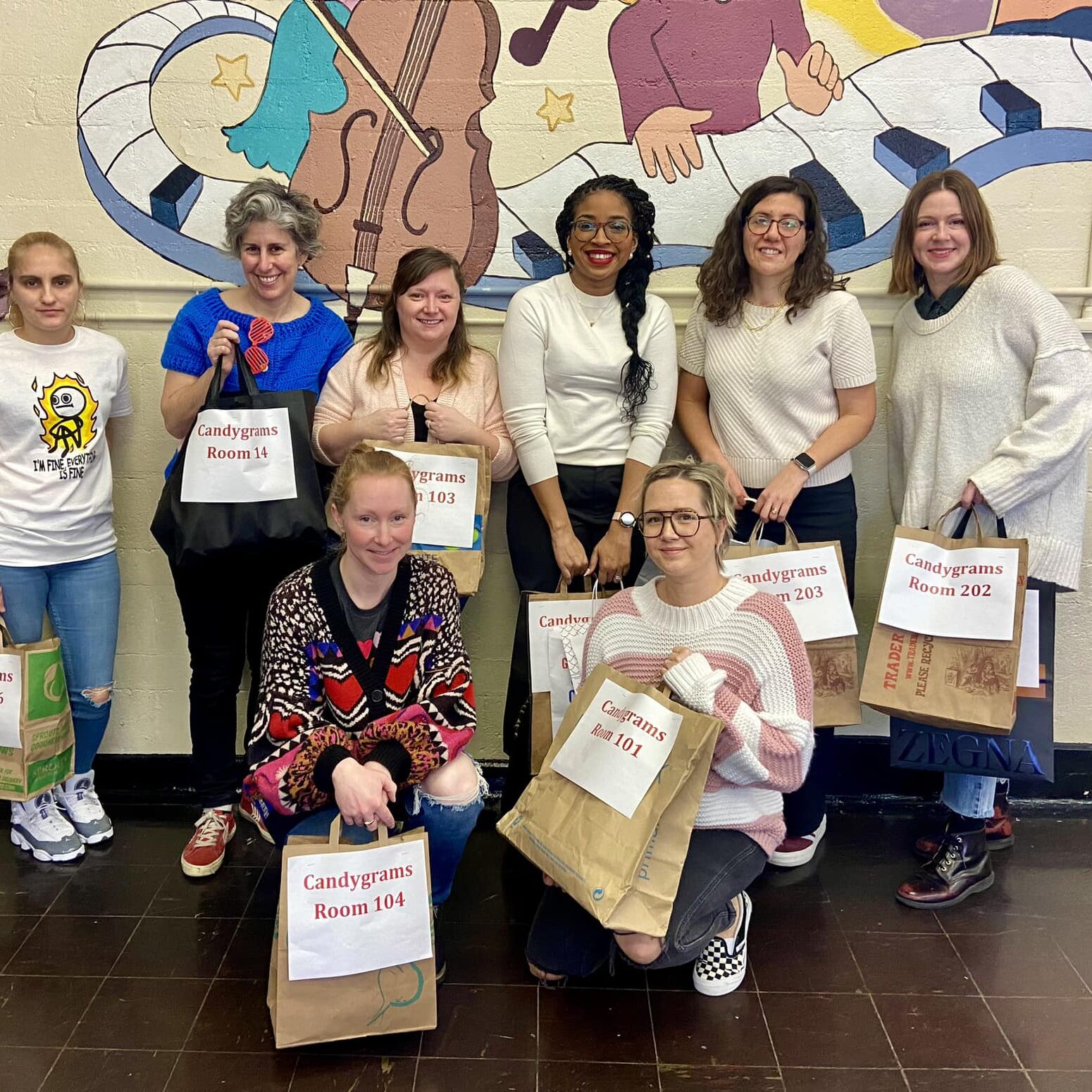 Abram Jenks School Home and School Association Volunteers Abram Jenks School Home and School Association members stand together holding bags during a school community activity, showing family and staff involvement in school events.